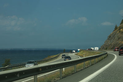 Cars on road with sea in background