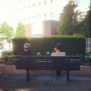 Men sitting on bench in city