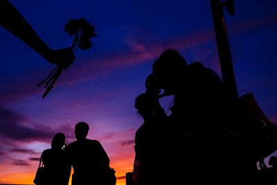 Low angle view of silhouette friends against sky during sunset