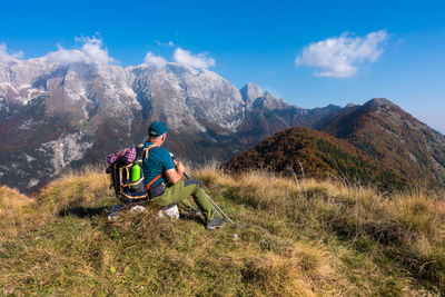 Rear view of man riding horse on mountain against sky