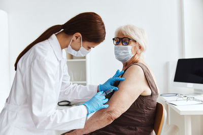 Doctor vaccinating senior woman at clinic