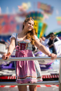 Smiling young woman standing at amusement park