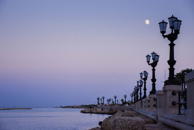 Street light by sea against clear sky at dusk