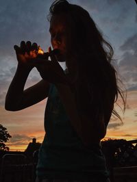 Woman smoking pipe at sunset