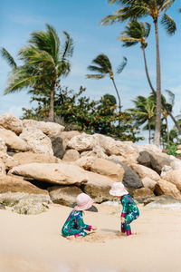 Rear view of people on rock by palm trees