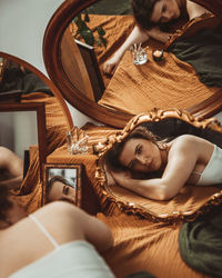 Beautiful young woman lying infront of different mirrors.