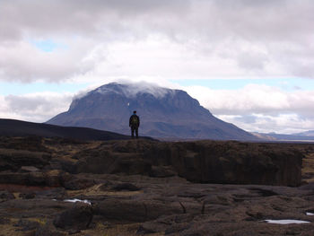 Rear view of man standing on rock against sky