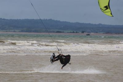 Man fishing in sea against sky