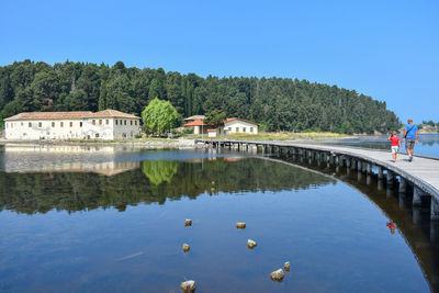 People pier over lake against clear blue sky