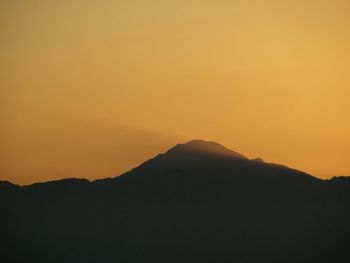 Scenic view of silhouette mountains against orange sky