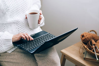 Midsection of woman using laptop at home