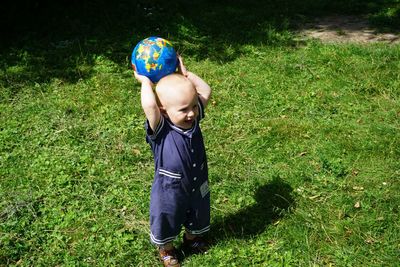 Smiling baby boy playing with ball at back yard