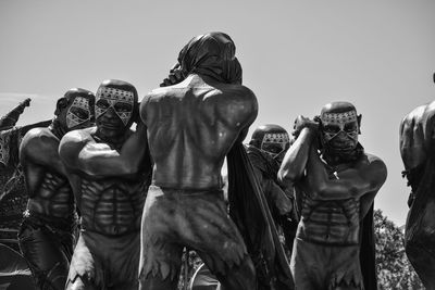 People photographing sculpture against clear sky