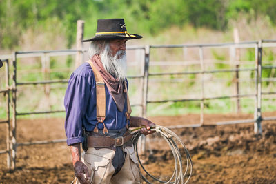 Senior man wearing hat standing on agricultural field