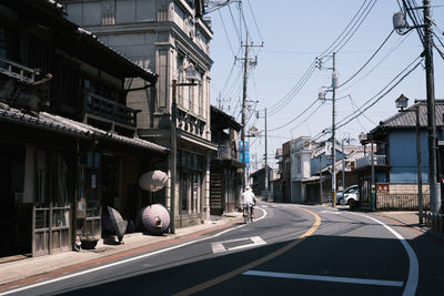 Vehicles on road amidst buildings in city against sky