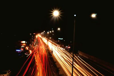 Light trails on city street against sky at night