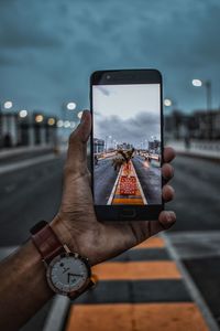 Midsection of person holding smart phone against sky