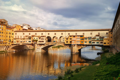 Arch bridge over river in city against sky