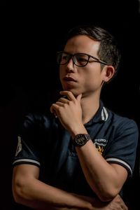 Portrait of boy sitting against black background