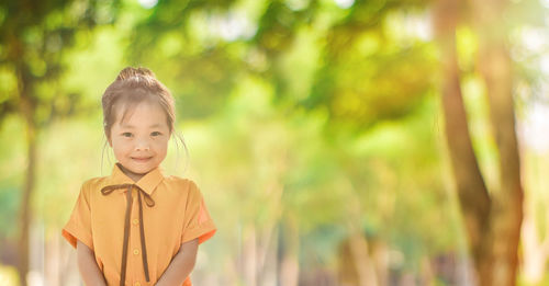 Portrait of smiling boy standing against trees