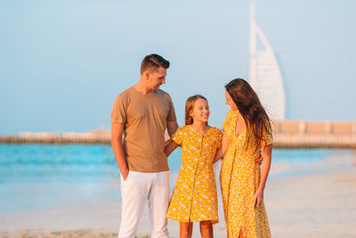 Rear view of friends standing by sea against sky