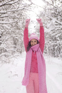 Woman raise your hands up. woods in pink clothes a jacket a knitted scarf. snowy forest in winter