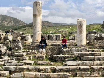 Full length of couple sitting on historic place