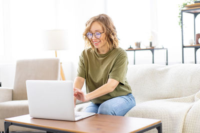 Young woman using phone while sitting on sofa