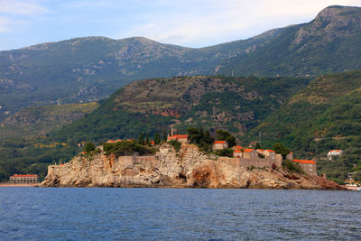 Sveti stefan by adriatic sea against mountains