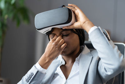 Young african american business woman suffering from eye strain after using vr headset at workplace