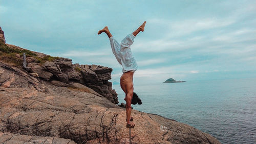 Young adult man doing circus acrobatic handstand upside down on mountain in brazil during day light