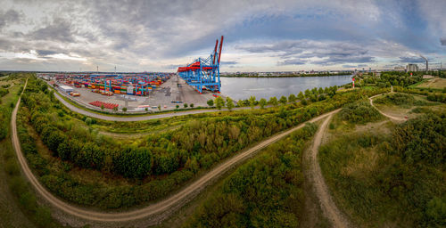 Shipping yard by river against sky