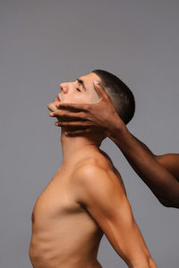 Side view of young man looking over white background