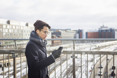 Handsome man with smartphone on footbridge