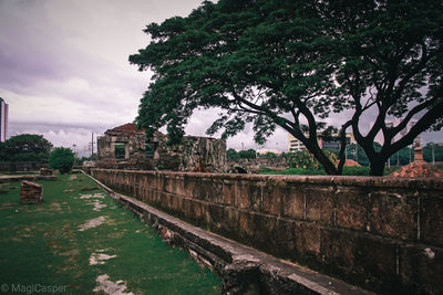 Old building by wall against sky