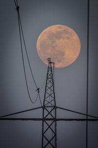 Low angle view of electricity pylon against sky at night