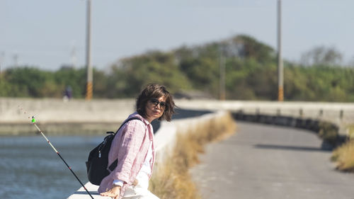 Side view of woman standing against river