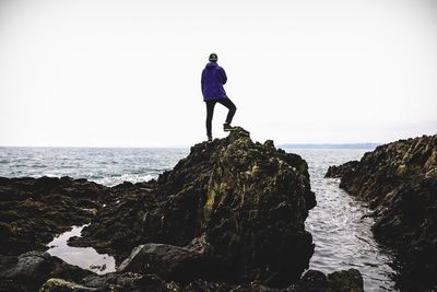 Rear view of man on rock at beach