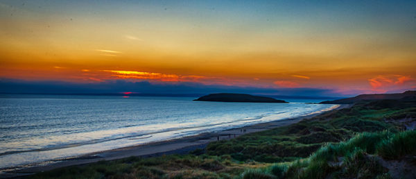 Scenic view of sea against dramatic sky during sunset