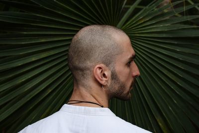 Rear view of young man looking away against palm leaf