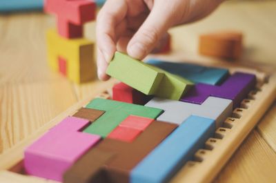 Close-up of hand holding multi colored pencils on table