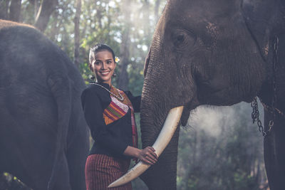 Portrait of smiling woman standing against trees