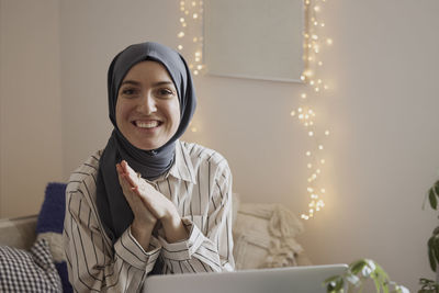 Portrait of happy businesswoman with hands clasped sitting in living room