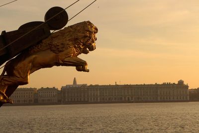 Close-up of lion sculpture on bow of boat with government building in background