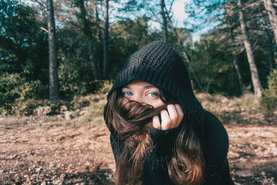 Portrait of young woman covering face with hair in forest