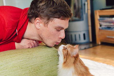 Young man looking at cat on sofa