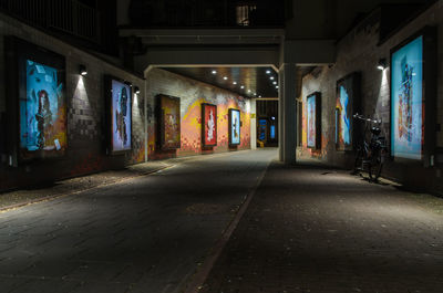 Empty road by illuminated buildings in city at night