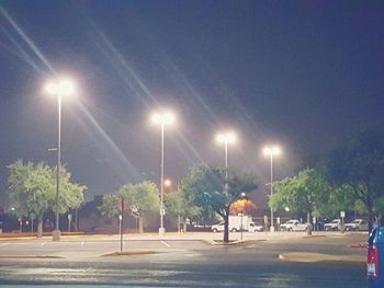 Illuminated street lights on road in city at night