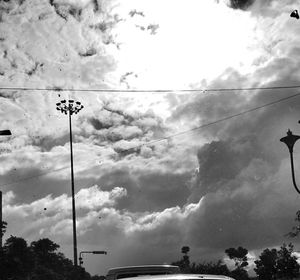 Low angle view of power lines against cloudy sky