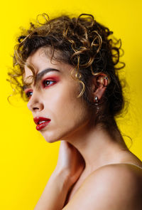 Close-up of woman looking away against yellow background